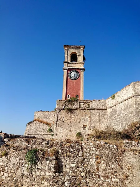 Uma Torre Relógio Topo Uma Parede Pedra Contra Céu Azul — Fotografia de Stock