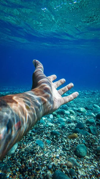 Pionowe Ujęcie Jego Ręki Pod Morzem Kamykami Ziemi — Zdjęcie stockowe