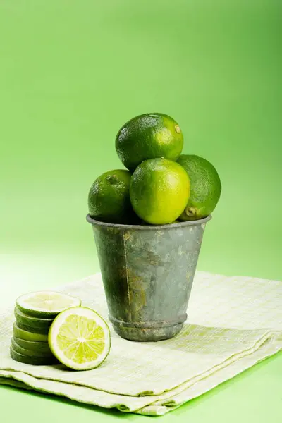 Een Verticaal Shot Van Verse Limoenen Een Maaltijdcontainer Groene Achtergrond — Stockfoto