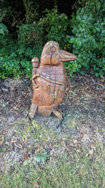 Bahçeye oyulmuş tahta bir heykelin dikey görüntüsü.