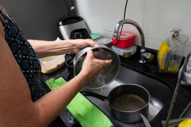 Mutfakta bir kadın bulaşık tepsisi ve çatal bıçak.