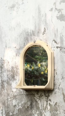 Eski bir duvara karşı küçük bir aynanın dikey görüntüsü..