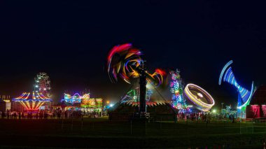 A long exposure shot of the Carnival Fair Rides at night clipart