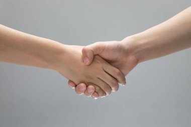 Gri bir arkaplan önünde birbirine dokunan iki elin yakın çekimi.