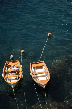 Vernazza, Cinque Terre, İtalya 'da sakin kayalık bir kıyıya demirlemiş iki tahta teknenin dikey çekimi.