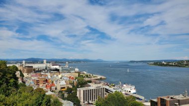 Bulutlu mavi gökyüzüne karşı binalarla çevrili bir göl.