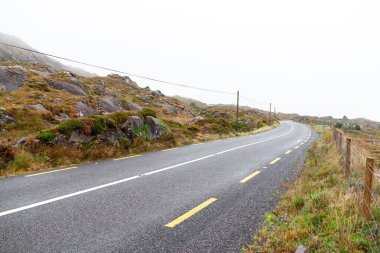 İrlanda 'da bulutlu bir gökyüzünün altındaki Kerry Yolu.
