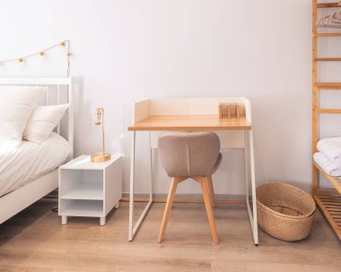 Bir komodinin, bir ahşap masanın ve yatağın yanına bir koltuk..