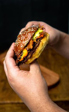 Çedar peynirli ve domuz pastırmalı sulu burger sandviçi. Siyah arka planda izole edilmiş.