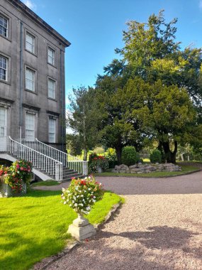 Güneşli bir günde binanın önündeki güzel bir bahçenin dikey görüntüsü.