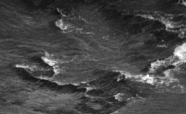 Okyanusun dalgalı sularının siyah-beyaz görüntüsü.