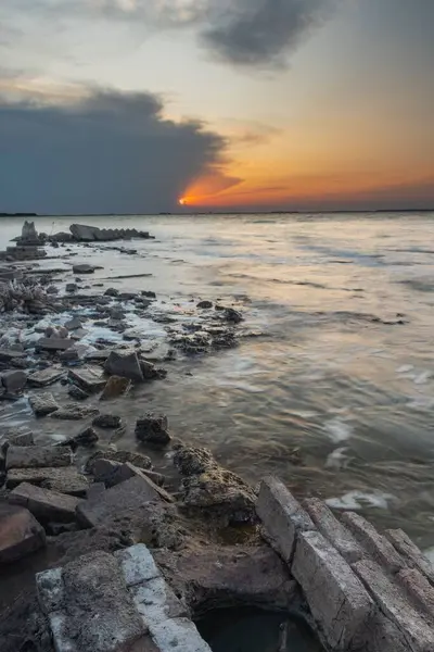 Eine Vertikale Langzeitbelichtung Von Meereswellen Die Bei Sonnenuntergang Die Küstensteine — Stockfoto