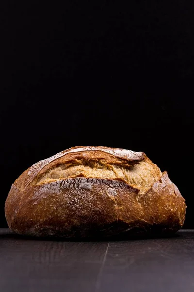 在黑暗的木制背景上一张圆形面包的垂直截图 — 图库照片