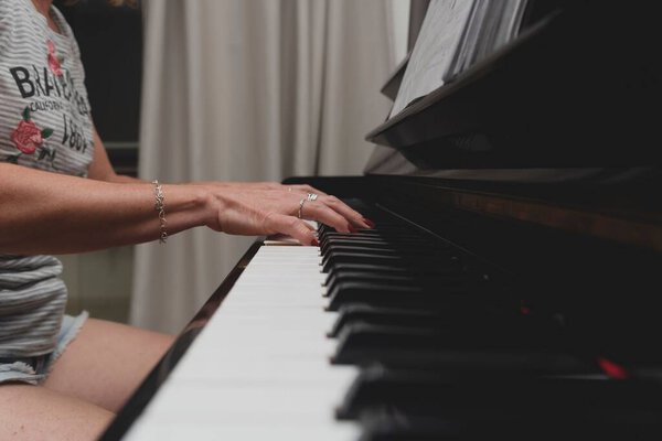 Красивая бразильская пианистка трогает клавиши пианино, играет на фортепиано. Концепция преподавания музыки и искусства. Расслабиться и повеселиться.