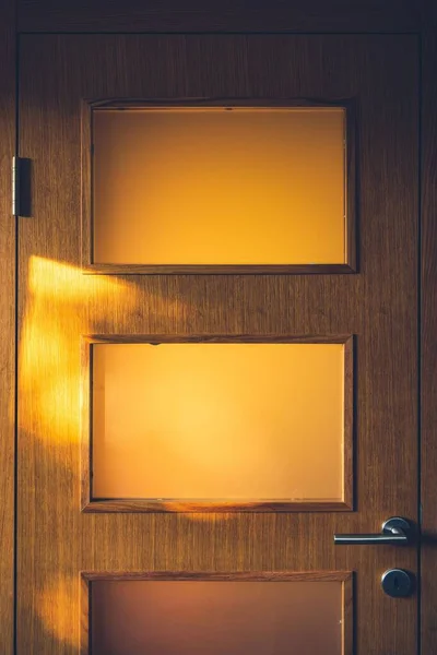 黄色の三角形と灰色の金属製のドアハンドルを持つ茶色の木製のドアの垂直ショット — ストック写真