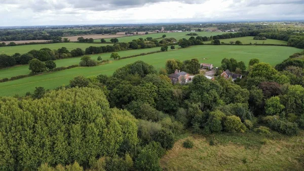 在多云的天空下 英格兰的一座由绿树和田野环绕的小房子组成的天线 — 图库照片