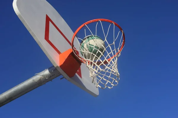 Arka Planda Mavi Gökyüzü Olan Bir Basketbol Topu Çemberin Içinden — Stok fotoğraf