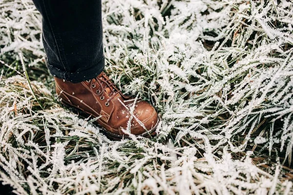 一个穿着棕色鞋子和牛仔裤站在结冰的草地上的人 — 图库照片