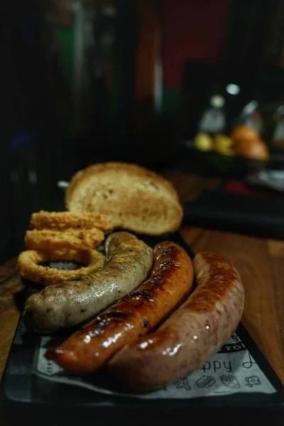 Een Verticale Close Van Braadworst Met Enkele Uienringen Ketchup Broodschijfjes — Stockfoto