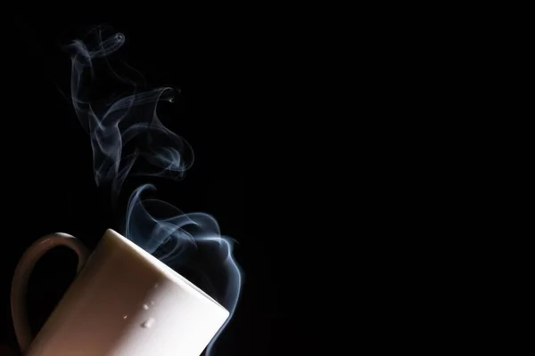 煙が出てくる黒の背景に白いカップの閉鎖 — ストック写真