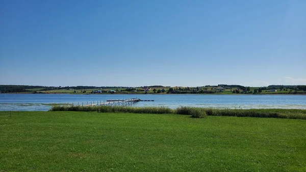 Голубое Небо Над Спокойным Озером Снятое Травяного Поля — стоковое фото
