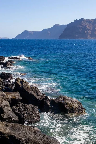 ギリシャのサントリーニ島の岩の海岸を打つ波の垂直ショット — ストック写真