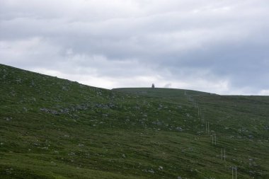 Norveç 'te gökyüzünde gri bulutların altında Vestkapp' ta yeşil bir sarp
