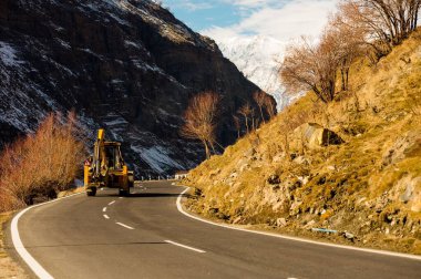 Dağlarda kar ve ağaçlar mavi gökyüzü ve bulutlar bir arka plan üzerinde yolun kenarında kaplı asfalt yoldan doğal kış görünümü