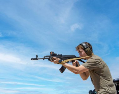 Arizona Yaz Tatlısı 'nda güneşli bir günde dürbünlü AK-47 otomatik tüfeği nişan alan kulaklı bir adam.
