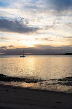 Gün batımında denizde yüzen bir teknenin dikey görüntüsü.