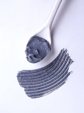 Beyaz zemin üzerinde kaşık olan bir kömür kil dokusu.