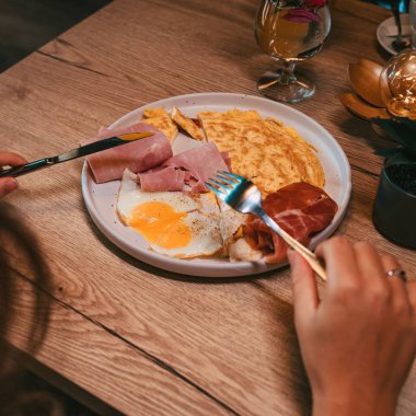 Beyaz bir tabakta servis edilen yumurta, omlet ve jambon manzarası.