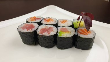 Sekiz parça lezzetli suşiyle dolu beyaz bir tabağın yakın çekimi.
