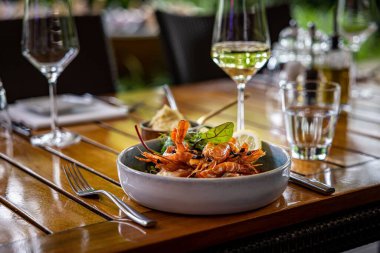 Karidesten yapılmış yuvarlak bir tabakta akşam yemeği ve ahşap bir masada sızlanmayla servis edilen yeşil