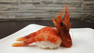 Bir Nigirzushi 'nin servis edildiği beyaz bir tabağın yakın çekimi.