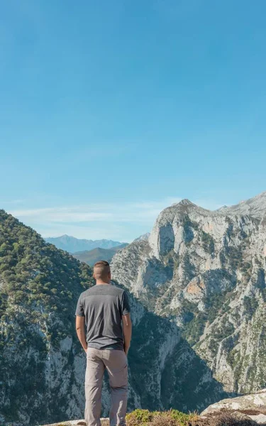 一个男人站在光芒四射的岩石群山前 — 图库照片