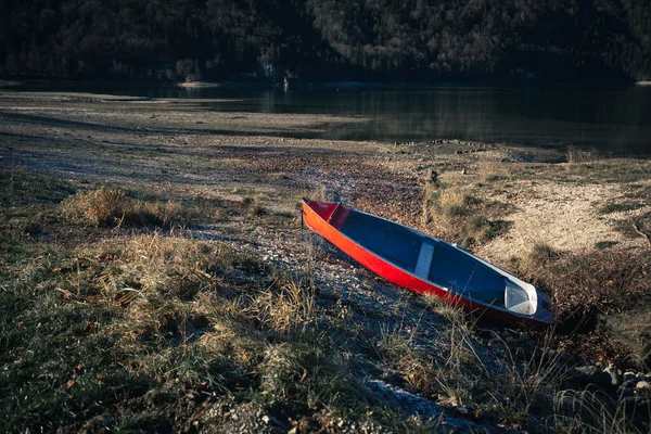 Крупный План Заброшенной Красной Лодки Земле Неподвижного Озера Неподалеку — стоковое фото