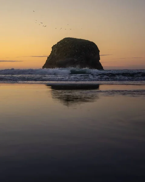 夕阳西下的海滩上 大海中巨大的岩层与泡沫般的海浪的垂直拍击 — 图库照片