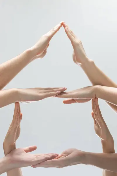 Tiro Vertical Ajudar Mãos Fazer Uma Pirâmide Frente Fundo Cinza — Fotografia de Stock