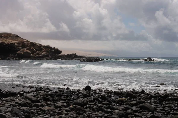 Beach Black Stones Ripples Turbulent Sea Clouded Sky — Stock Photo, Image