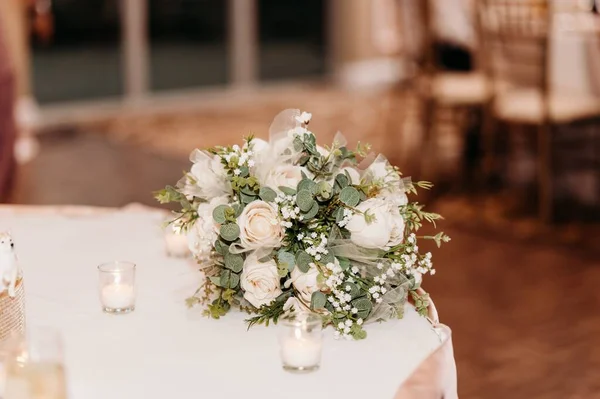 白いキャンドルのテーブルの上に白いバラと結婚式の花束の選択的な焦点 — ストック写真