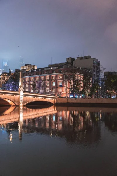一个城市景观 有桥梁和河岸建筑 夜间反映在水面上 — 图库照片