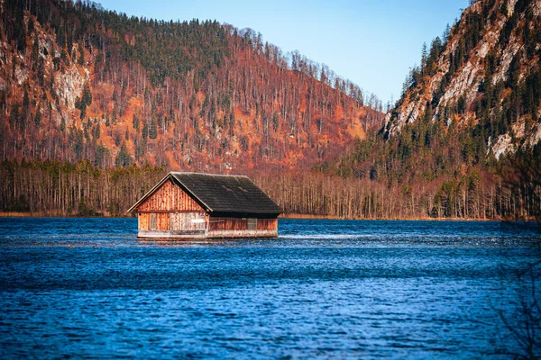一座木头房子 建在一个蓝色的湖心 四周环绕着一片秋天的树木 — 图库照片