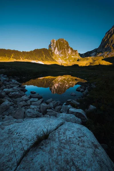 Tiro Vertical Das Formações Rochosas Refletido Lago Dia Ensolarado — Fotografia de Stock