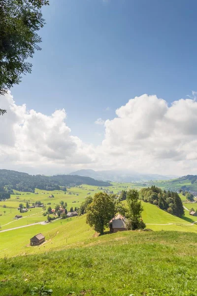 高い丘に囲まれた緑の谷の村の上の美しい風景 白い雲と青空の下で — ストック写真