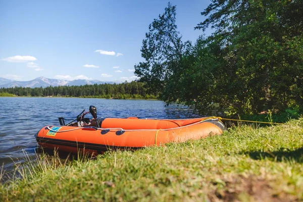 背景に山のある湖にはオレンジのモーターボートが停泊している — ストック写真