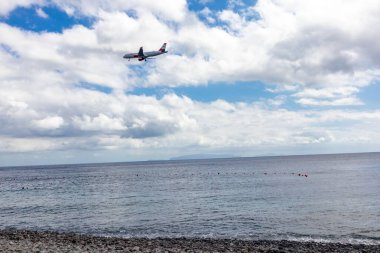 Mavi gökyüzünde uçan bir Ryanair uçağı Atlantik Okyanusu üzerinde bulutlarla Madeira, Portekiz