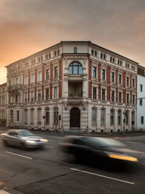 Paderborn 'da gün batımında ön planda arabalar olan bir binanın dikey görüntüsü, Almanya