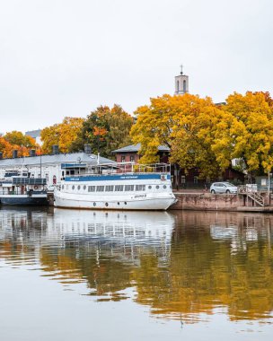 Aura nehri, sonbaharda Finlandiya 'nın Turku kentinde sonbahar yaprakları arasında gemilerle görülür.