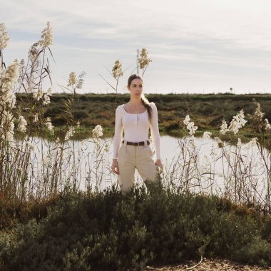 Uzun kamışların yanında poz veren genç ve şık bir dişi göl kıyısında büyüyor.
